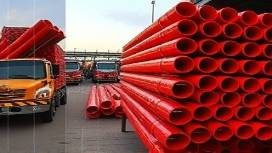 commercial PVC pipe, robust, stacked for transport, photorealistic, loading dock full of heavy vehicles, highly detailed, workers securing loads, durable construction, red, dusk lighting, shot with a 55mm lens.